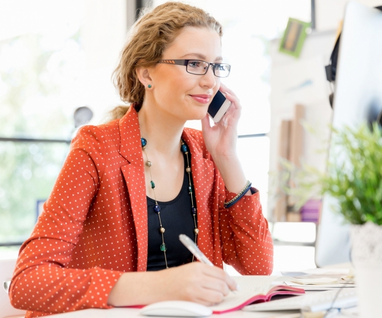 young-woman-holding-mobile-phone-in-office-PE9ARDR-768x640